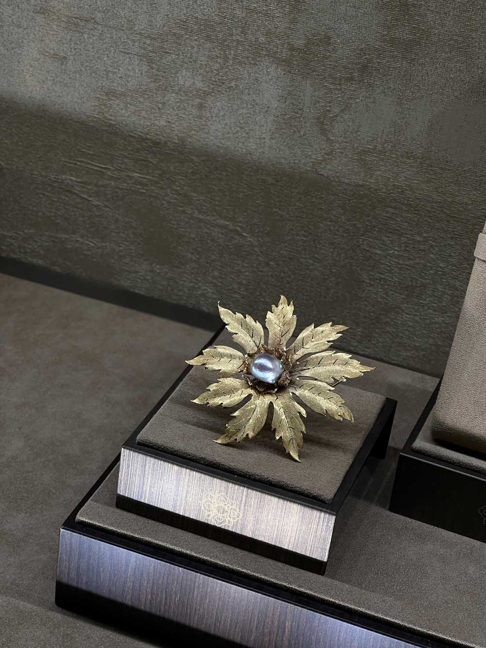 Antique gold leaf brooch with central grey pearl on a jeweller's stand — fine jewelry and diamonds advisory