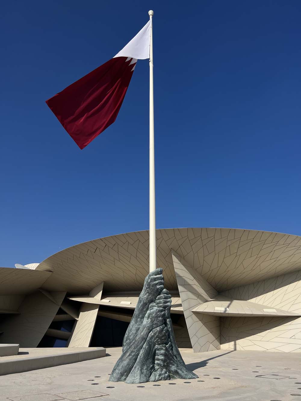 Qatar national flag and a bronze sculpture before the National Museum of Qatar designed by Jean Nouvel, Doha — AN Art Advisory Middle East presence