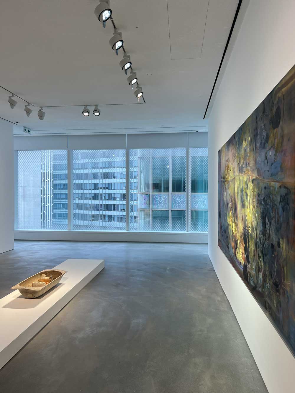 Gallery space with a large abstract dark painting and a wooden vessel sculpture on a plinth — art advisory acquisition context