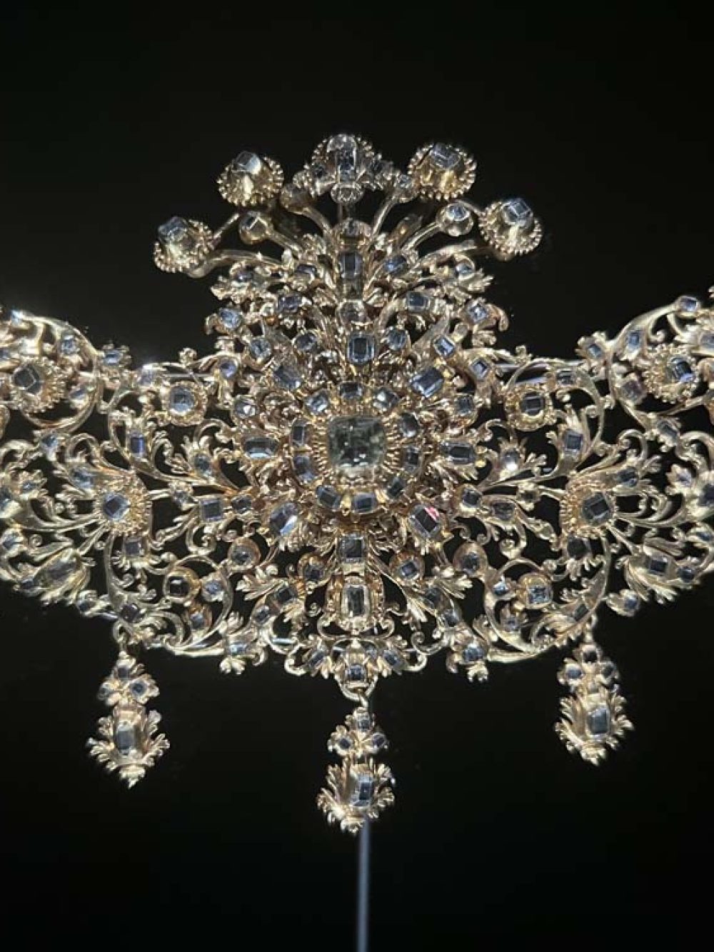 Historic Baroque diamond bodice ornament with intricate scrolling silver and gold metalwork, on a black velvet background — antique jewelry advisory and valuation