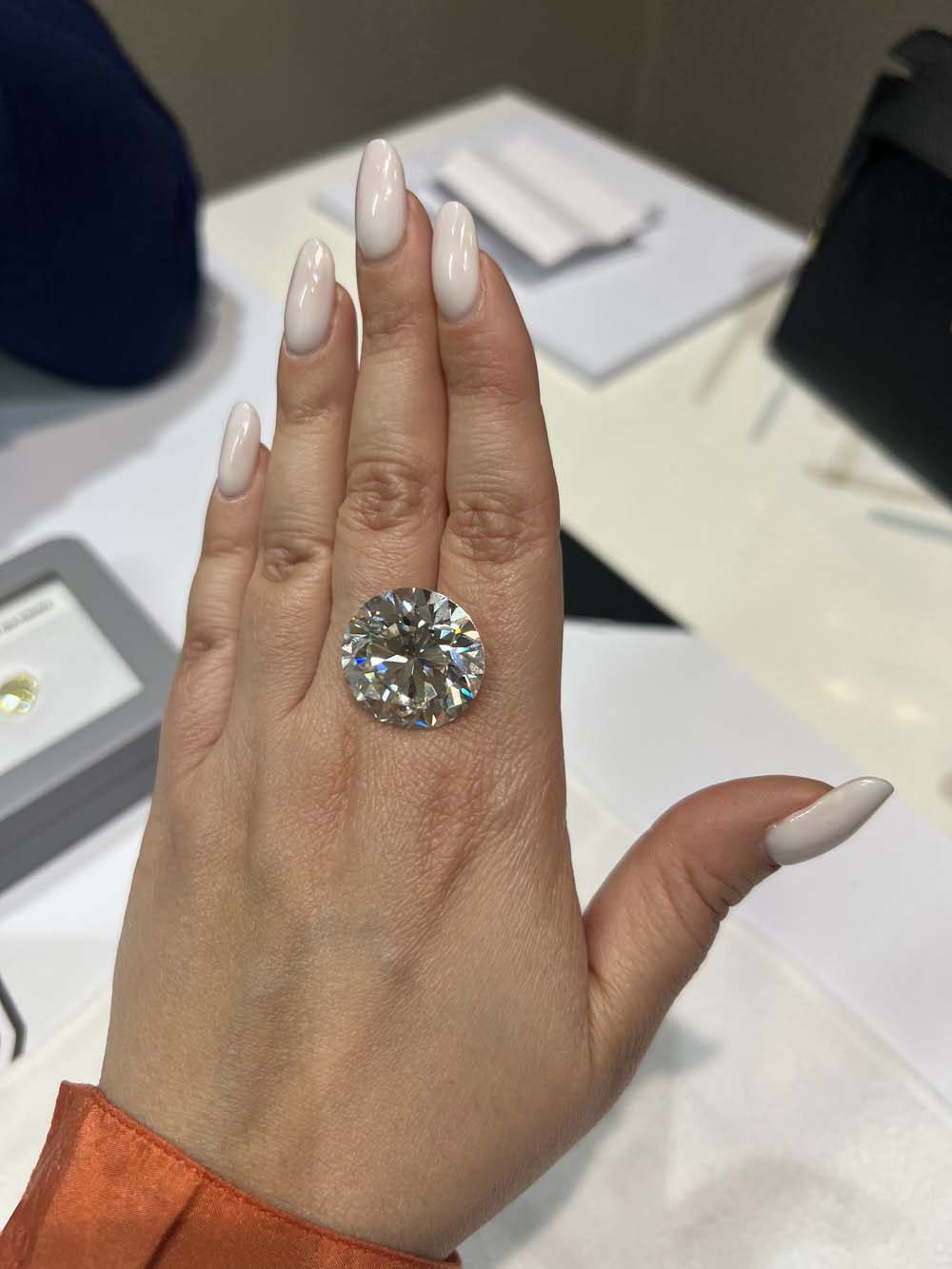 Exceptionally large round brilliant-cut natural diamond balanced on an open palm, demonstrating extraordinary scale — natural diamond advisory
