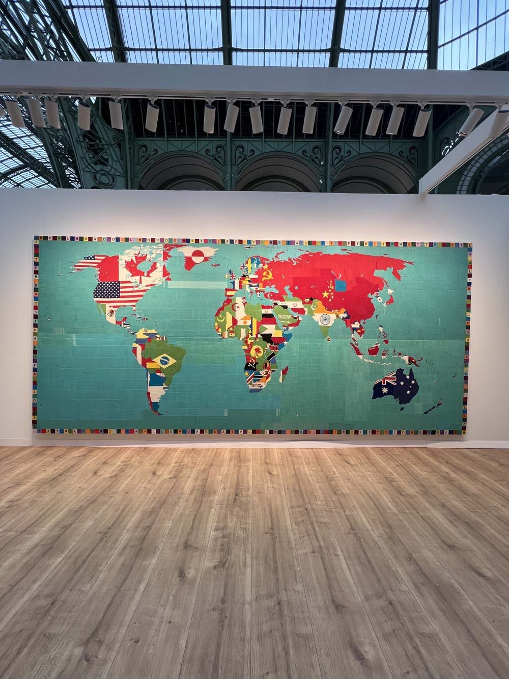 Giant world map painting with national flags on display at the Grand Palais Paris — international art appraisal and wealth advisory