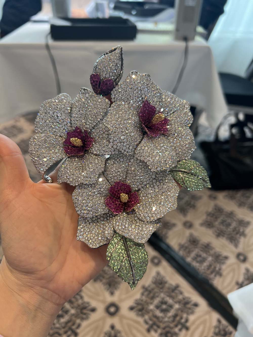 Large floral brooch with white diamond pavé flowers, ruby centers and green enamel leaf accents — fine jewelry collection management and advisory