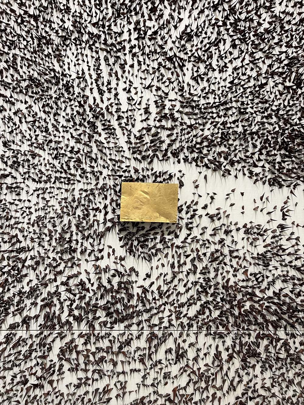 Contemporary installation: a gold cube surrounded by black ant figures — art as wealth, advisory context