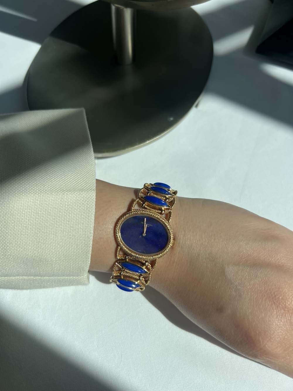 Vintage gold bracelet watch with lapis lazuli dial and matching lapis lazuli cabochon-link bracelet, worn on wrist — fine jewelry appraisal and wealth advisory