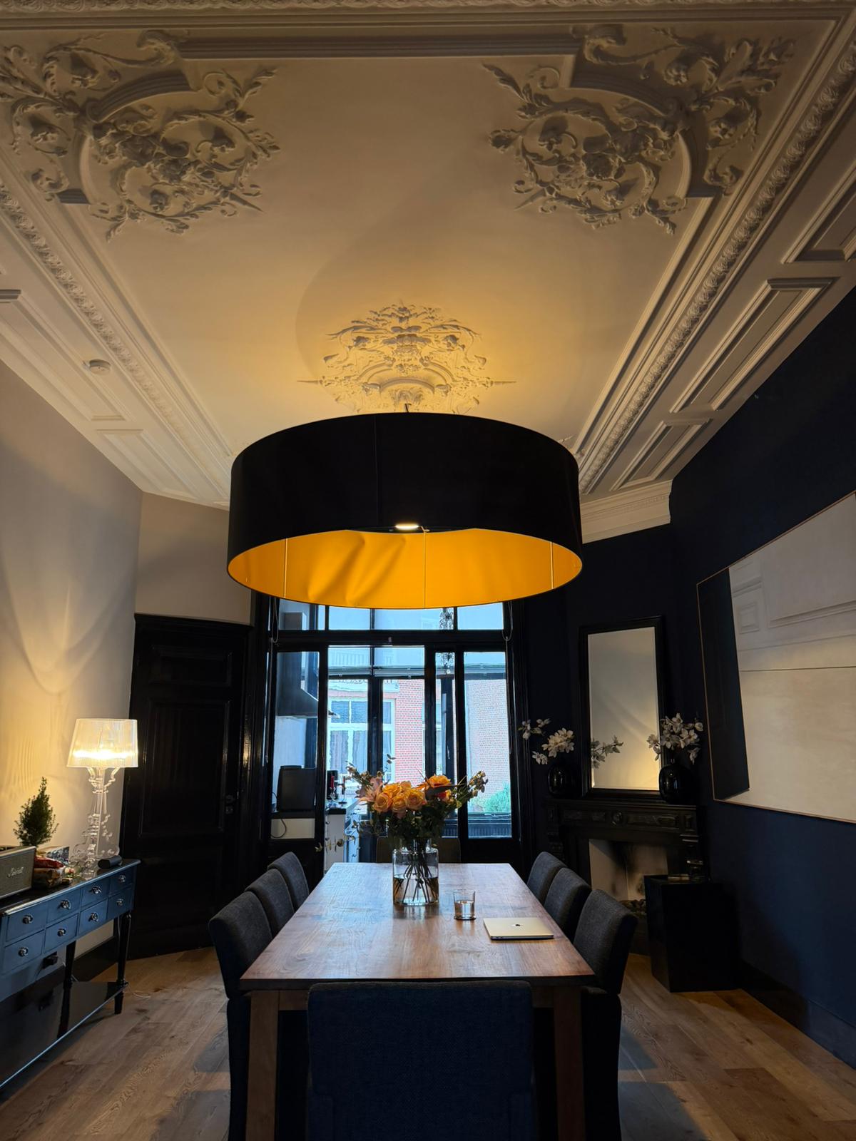 AN Art Advisory conference room in The Hague with ornate Baroque plasterwork ceiling, large black and gold pendant lamp and a long wooden table